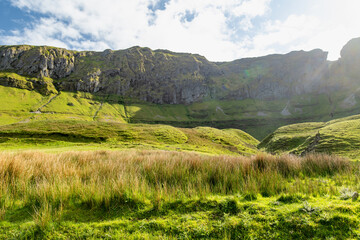 Obraz premium Gleniff Horseshoe in County Sligo, Ireland, with rolling grassland beneath steep limestone mountains and bright clouds. A scenic drive through one of Irelands classic valleys.