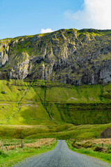 Obraz premium Gleniff Horseshoe in County Sligo, Ireland, with rolling grassland beneath steep limestone mountains and bright clouds. A scenic drive through one of Irelands classic valleys.
