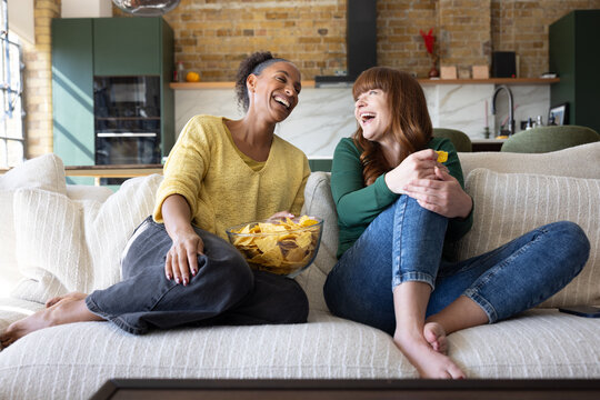 Female friends watching entertainment together at home