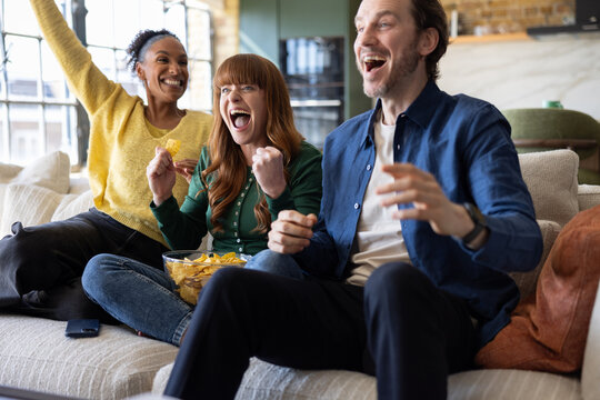 Friends cheering with snacks during a football match