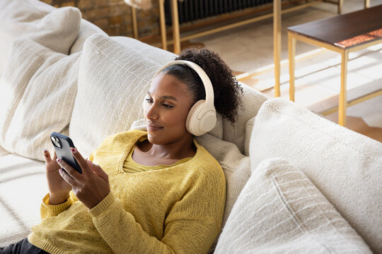 Smiling Woman Enjoying Music with Phone on Couch