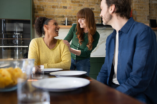 Friends sharing laughter and drinks in a cozy kitchen.