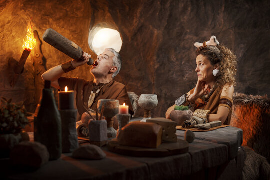 Rude Caveman Drinking from Bottle During Date &ndash; Prehistoric Bad Manners and Relationship Problems Concept