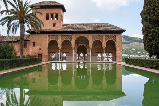 Alhambra Partal Palace standing majestically with its intricate Moorish architecture, reflecting beautifully in the tranquil pool, showcasing historical grandeur and design