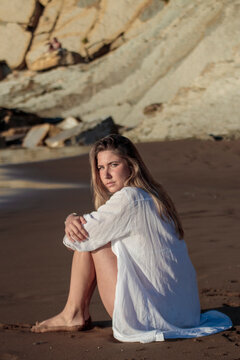 Woman sitting contemplating on a sandy beach