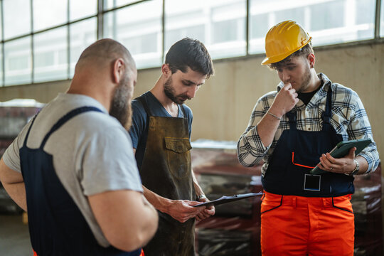 Manufacturing workers discussing daily tasks in factory warehouse