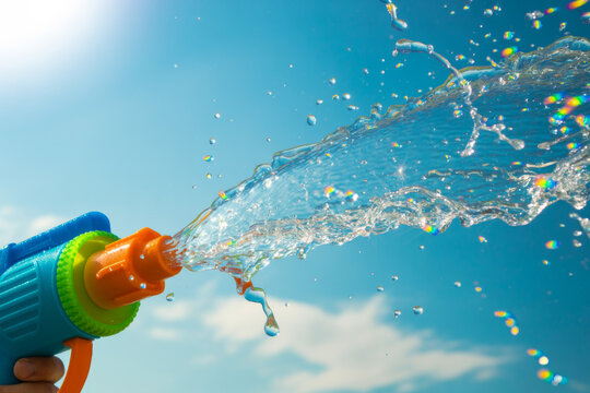 Water gun spraying water stream against blue sky background summer fun outdoor play