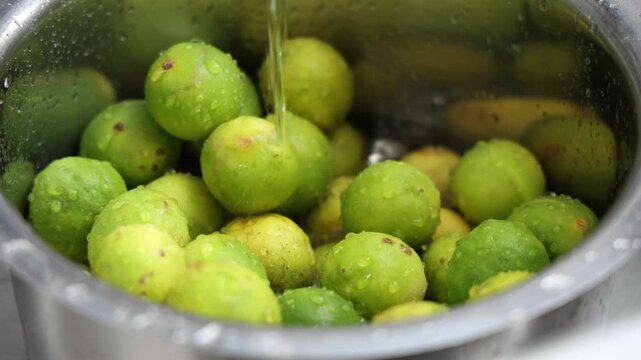 Pouring of water in vessel full of lemon, lime for cleaning