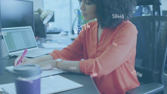 Woman checking sheet and picking pink pen, updating analysis while data overlay floating over desk