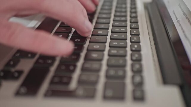 Hands of freelancer typing on silver notebook keyboard, close up view.