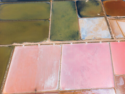 Aerial view of the colorful salt evaporation ponds at Salines des Trenc with vibrant pink and green rectangular pools, Campos, Islas Baleares, Spain.