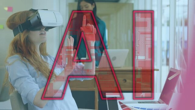 Seated woman wearing VR headset reaching office UI, testing red AI while peer working on laptop