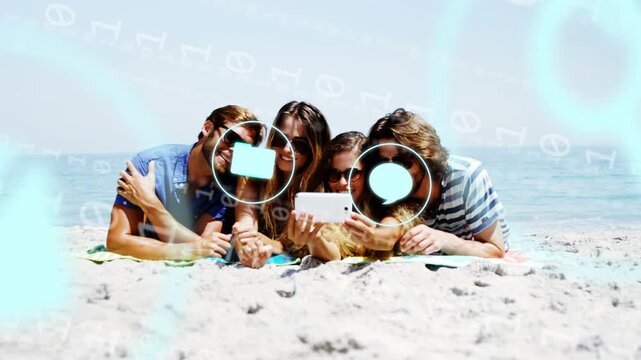 Friends lying on beach holding phone animating neon blue camera globe icons over group for ads
