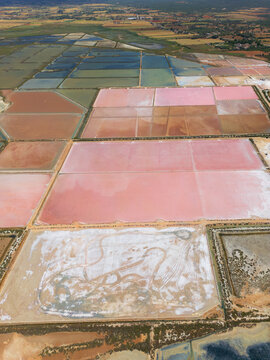 Aerial view of Salines des Trenc salt evaporation ponds with vibrant pink and blue water under daylight in Campos, Islas Baleares, Spain.