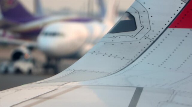 Close-Up Airplane Wing Detail at Airport With Taxiing Aircraft and Runway Background