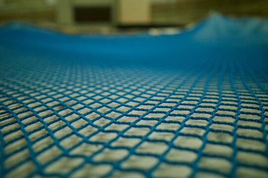 Close up of blue plastic mesh net pattern with selective focus, abstract industrial background of interlocking nylon grid texture