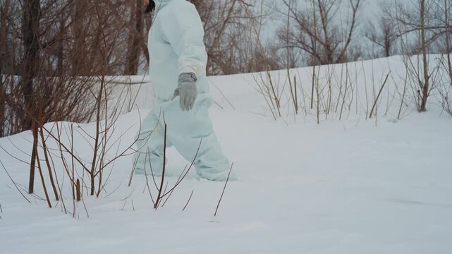 Scientist in hazmat suit trudging through deep snow at frozen abandoned research field, cautious steps, frostcovered shrubs, overcast sky, silent postapocalyptic mood, radiation monitor clipped