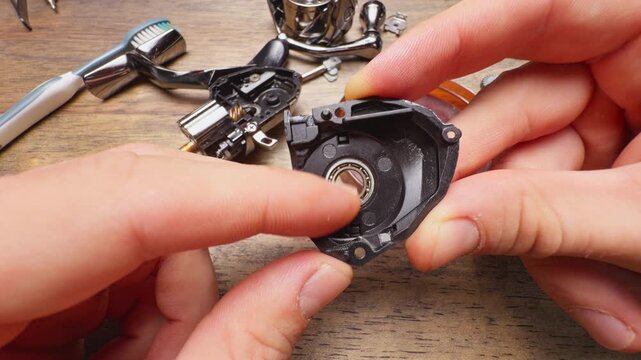 Close Up Macro Shot of Hands Checking Bearing Rotation Inside Fishing Reel Housing During Maintenance Repair, Precision Inspection of Angling Equipment Parts