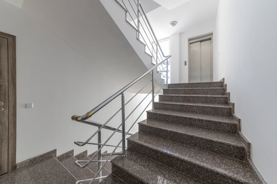 Modern stair case between floors. Stairs with metallic rail in modern building. Interior of a contemporary apartment or office building. Architecture and real estate background.