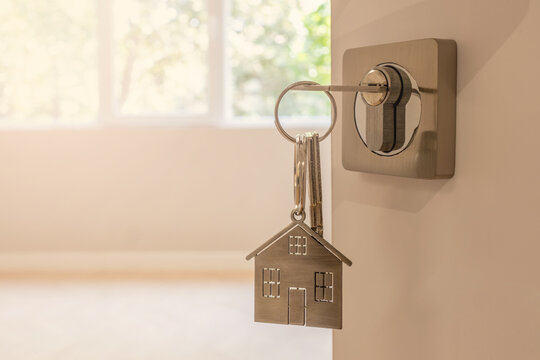 Open door to a new home with key and home shaped keychain. Mortgage, investment, real estate, property and new home concept