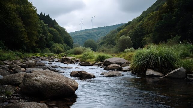 A lush river flowing through a dense temperate forest valley under a dramatic sky with modern wind turbines visible in the distance