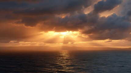 Obraz premium Dramatic shafts of golden sunlight pierce through heavy cloud covered skies over a vast ocean horizon