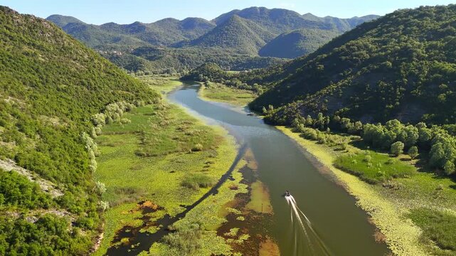 Aerial view of Rijeka Crnojevica between mountains flowing into Skadar Lake, Montenegro. Tourist boats are sailing on the lake.