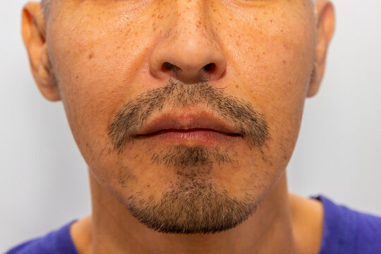 Close up portrait of an asian man with stubble and freckled skin. Natural facial texture and skincare concept. Male grooming and realistic details for dermatology or beauty advertisement.
