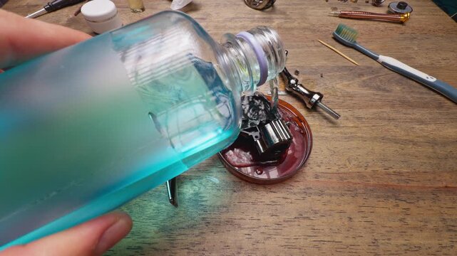 Close Up Macro Shot of Pouring Alcohol Cleaning Solution Over Spinning Fishing Reel Body During Maintenance Repair, Deep Degreasing of Internal Drive Mechanism
