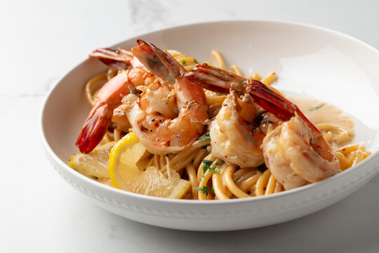 Shrimp pasta with lemon cream sauce and red peppers on a white plate