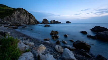 Obraz premium Tranquil seascape capturing the dramatic blue hour lighting at a rugged rocky coastline with distant sea formations