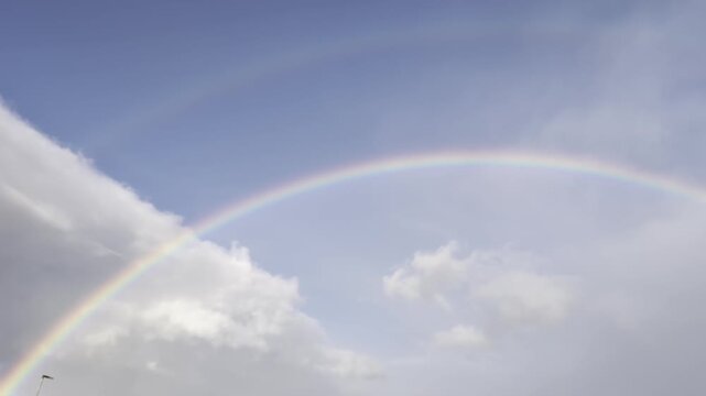 Doppio arcobaleno su cielo nuvoloso con luce naturale, fenomeno atmosferico raro e suggestivo che crea un&rsquo;atmosfera magica e contemplativa