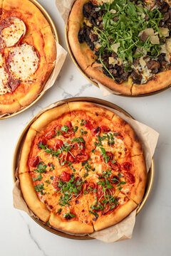 Assorted pizzas viewed from above on a light surface