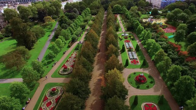 4K aerial view of Regent's Park Avenue Gardens with symmetrical Victorian flower parterres, tree-lined Broad Walk, stone fountains and Nash terraces in Central London.