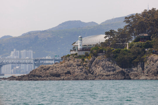 Nurimaru APEC House, Busan, South Korea, Dongbaek Park on Haeundae Dongbaekseom Island, with Dongbaekseom Lighthouse and mountain, Busan Bay marina skyline, conference center venue and memorial hall