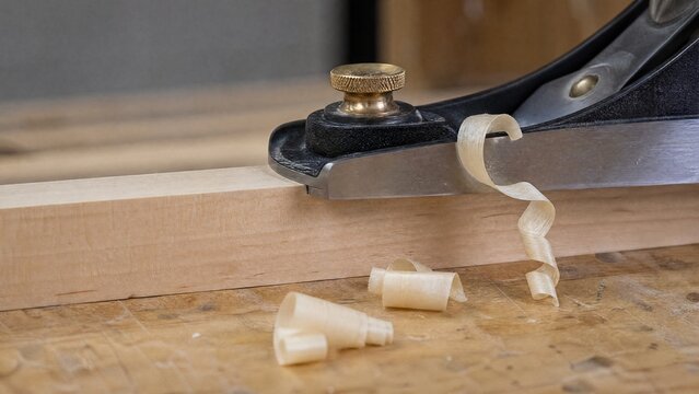 jointer. Close-up of a woodworking blade pressing against a wooden board, creating shavings. safety posters, maintenance manuals, designed for precision metalworking and fabrication facilities.