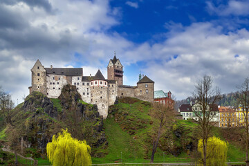 Fototapeta premium Medieval Loket Castle on a steep cliff, Czech Republic. Gothic stone fortress under blue sky with white clouds