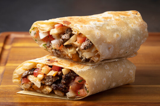 Beef wrap cut in half on wooden table close up