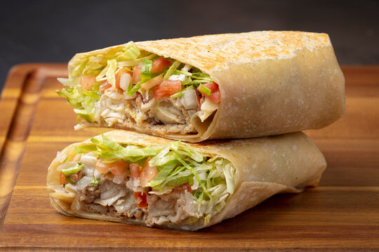 Chicken wrap cut in half on wooden table close up