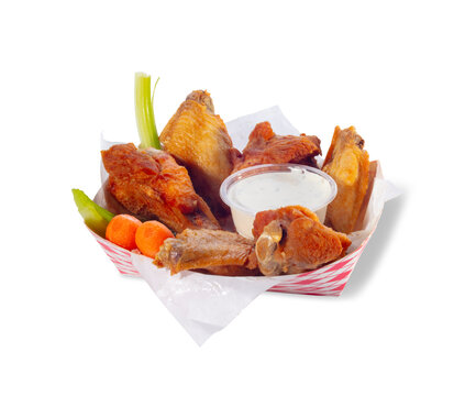 Crispy chicken with onion rings, vegetables and dipping sauce in a basket on white background