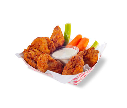 Crispy chicken wings with celery, carrots and dipping sauce in a basket on white background