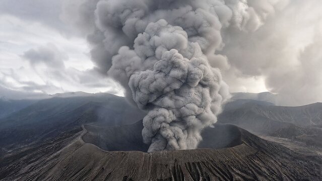 homogeneity. A thick plume of grey smoke rising from a volcanic crater, desolate landscape. ESG reports, sustainability campaigns, designed for sustainability communications and ESG reporting.