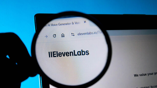 Closeup of a magnifying glass held over a laptop screen displaying the elevenlabs ai voice generator website