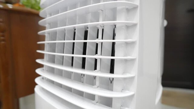 Close-up of white plastic air conditioner or cooler vent with protective black mesh grille. Industrial abstract background of ventilation system.