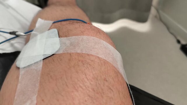 A detailed video of a physical therapy session showing muscle stimulation on a human knee. The footage captures the involuntary muscle movement caused by the electrostimulation device (EMS), highlight