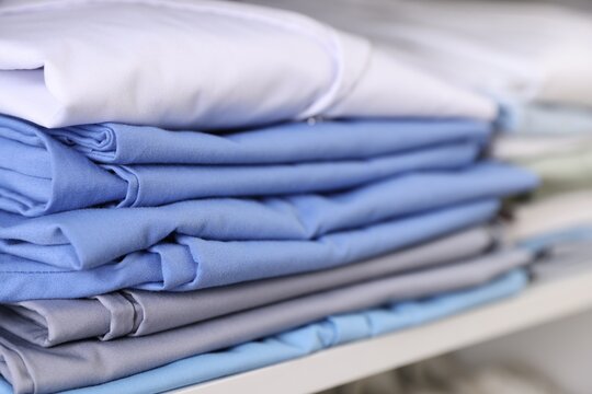 Different medical workers' uniforms on shelf indoors, closeup