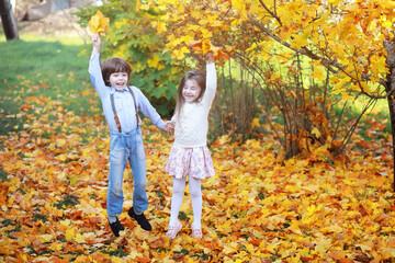 Naklejka premium Young family on a walk in the autumn park on a sunny day. Happiness to be together.