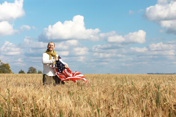 Fototapeta premium Man waving American flag standing in grass farm agricultural field , holidays, patriotism, pride, freedom, political parties, immigrant