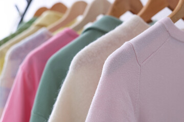 Obraz premium Different clothes hanging on rack against white background, closeup