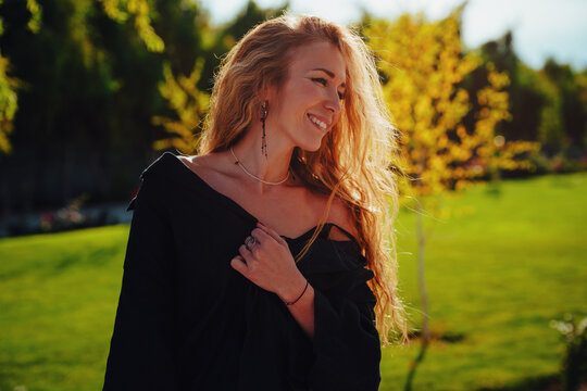 Portrait of beautiful smiling woman in a green garden at sunset